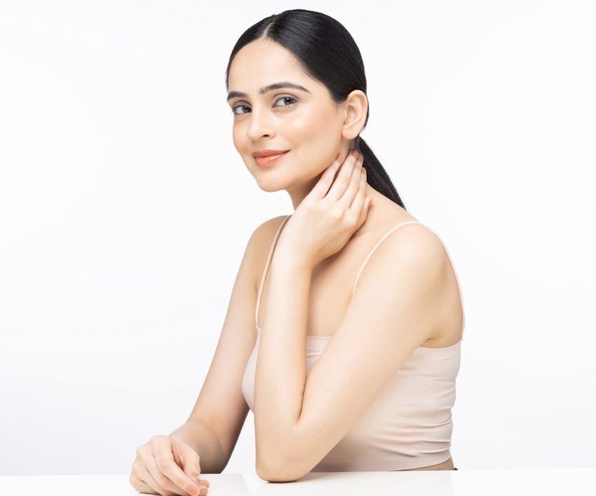 woman with low pony tail touching her neck