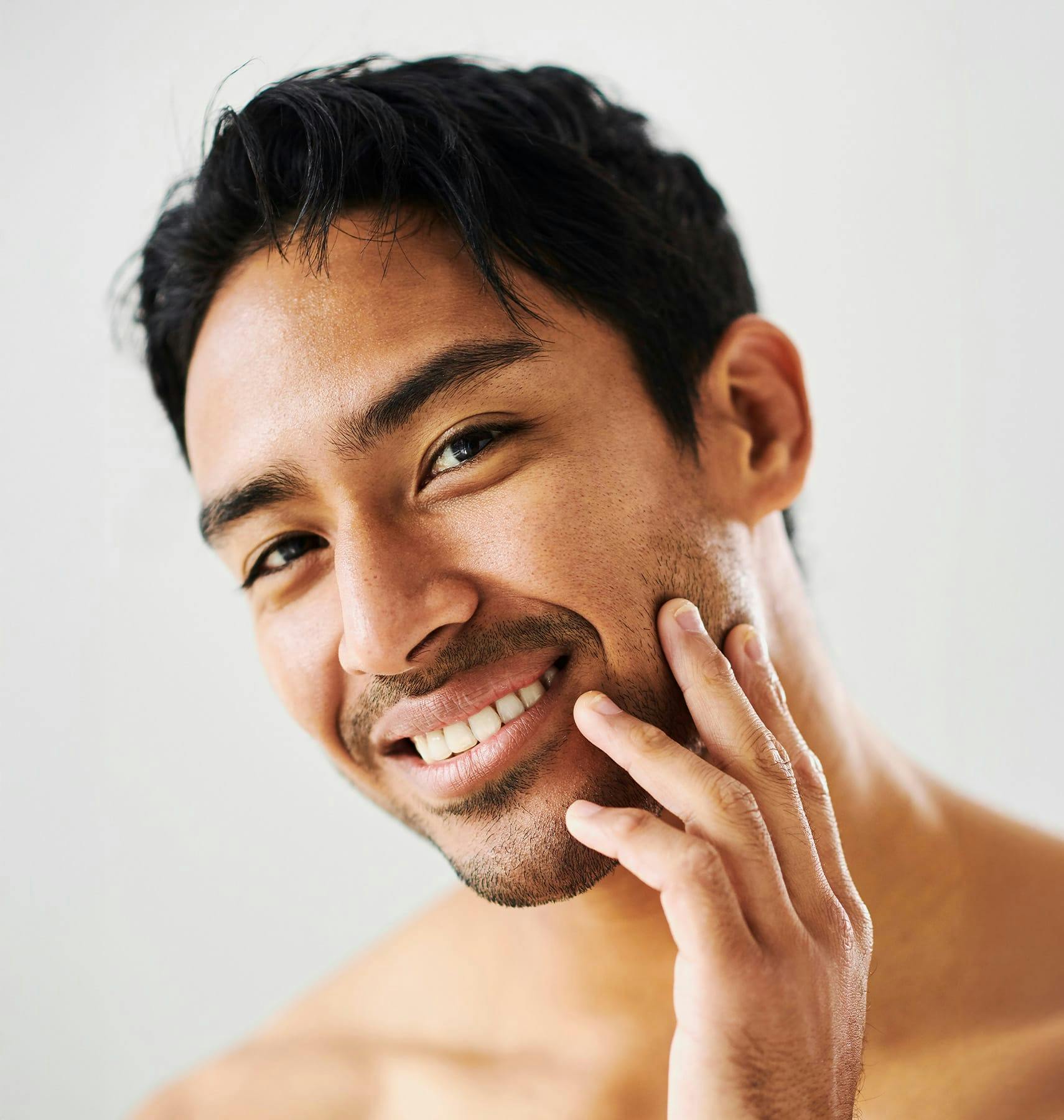 man leaning his head and touching his beard