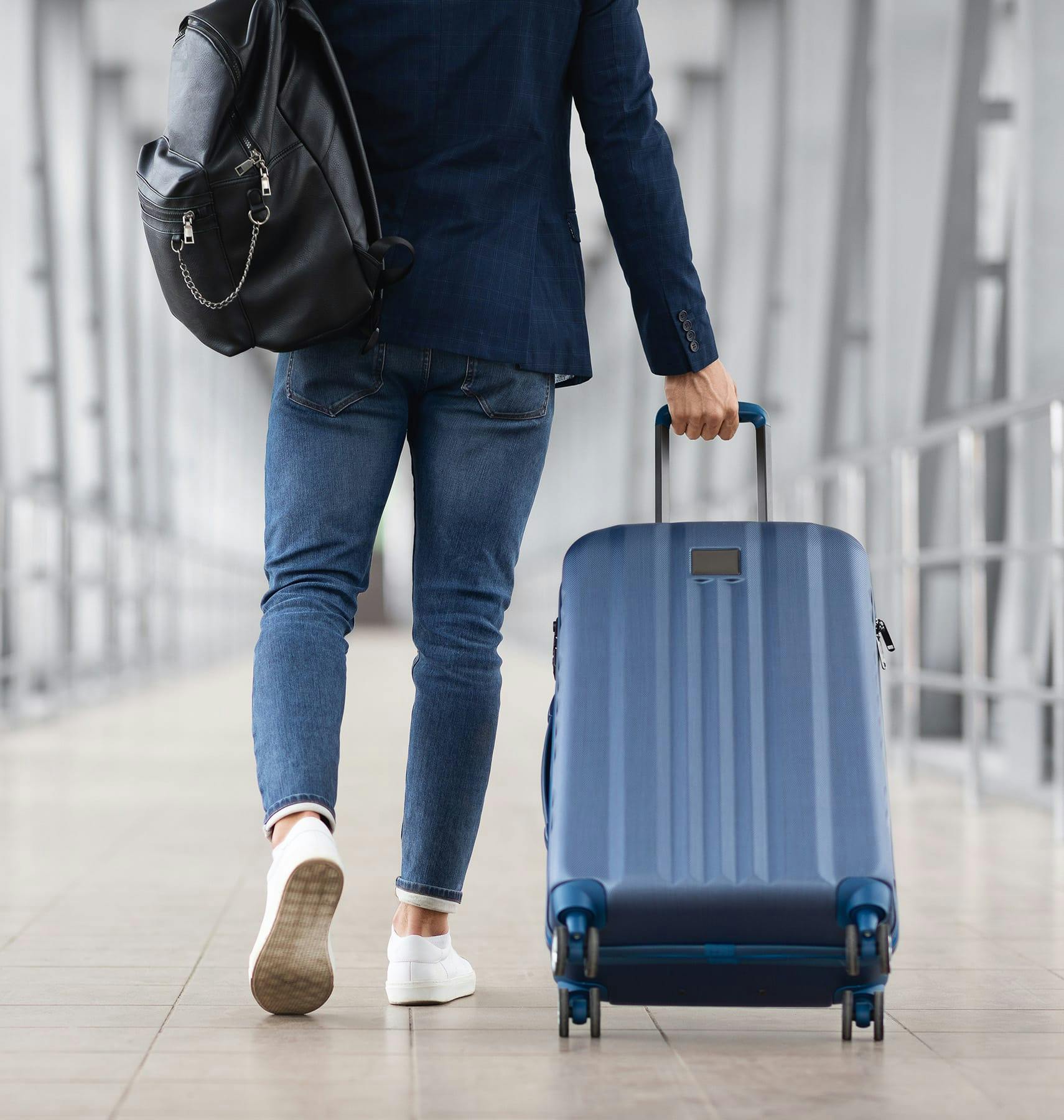 man walking away with bag and suitcase