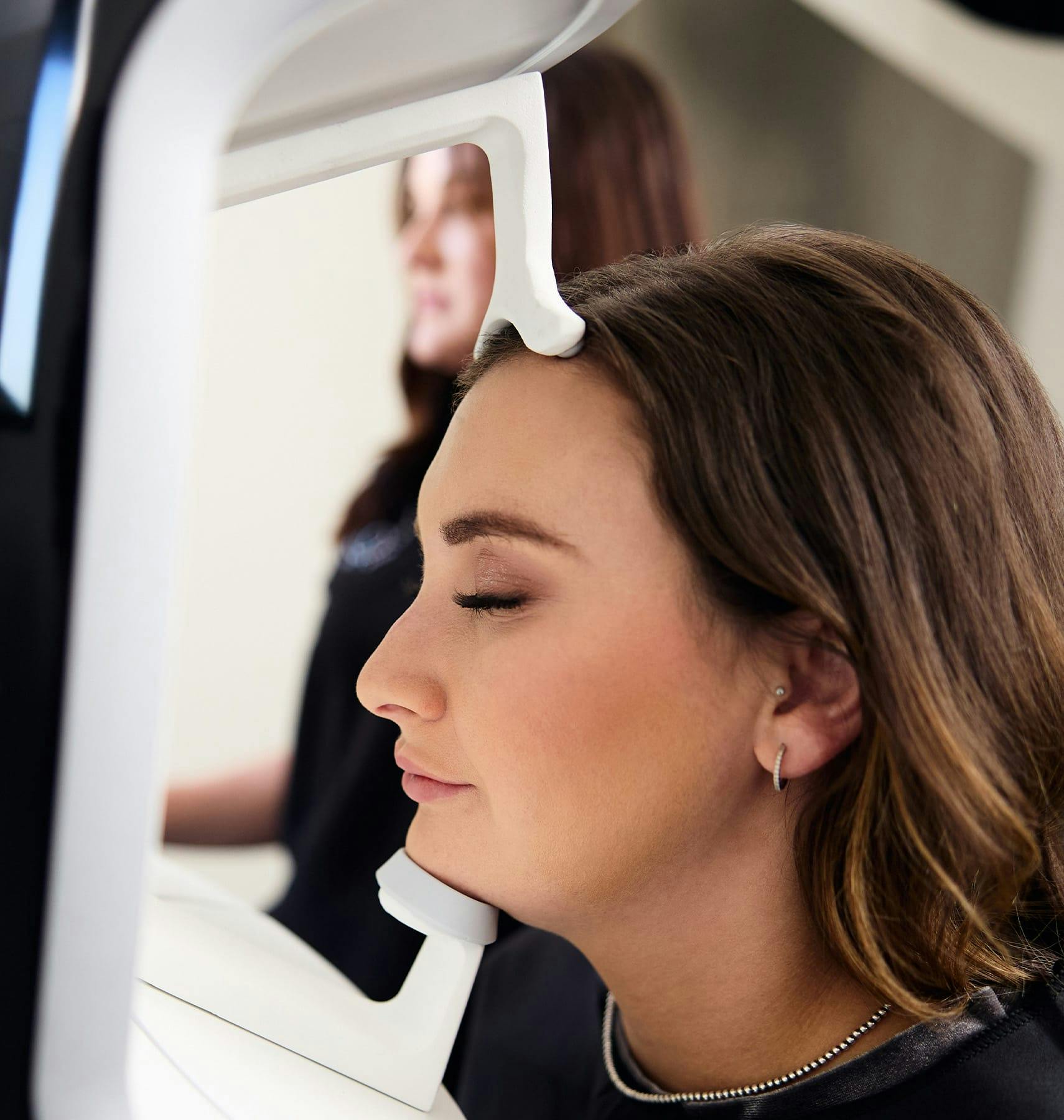 woman resting her head on 3D imaging machine
