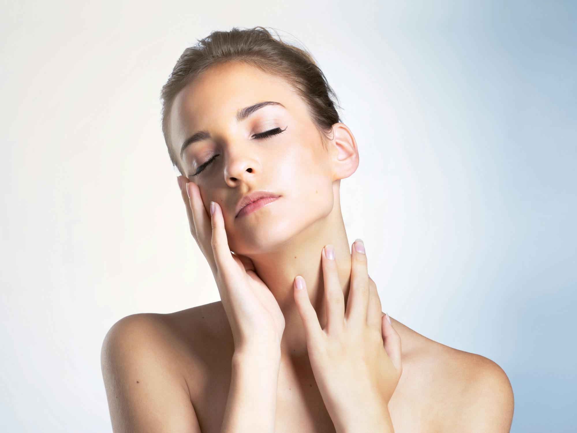 woman with smooth skin holding face and neck