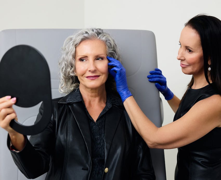 woman looking at herself in a handheld mirror