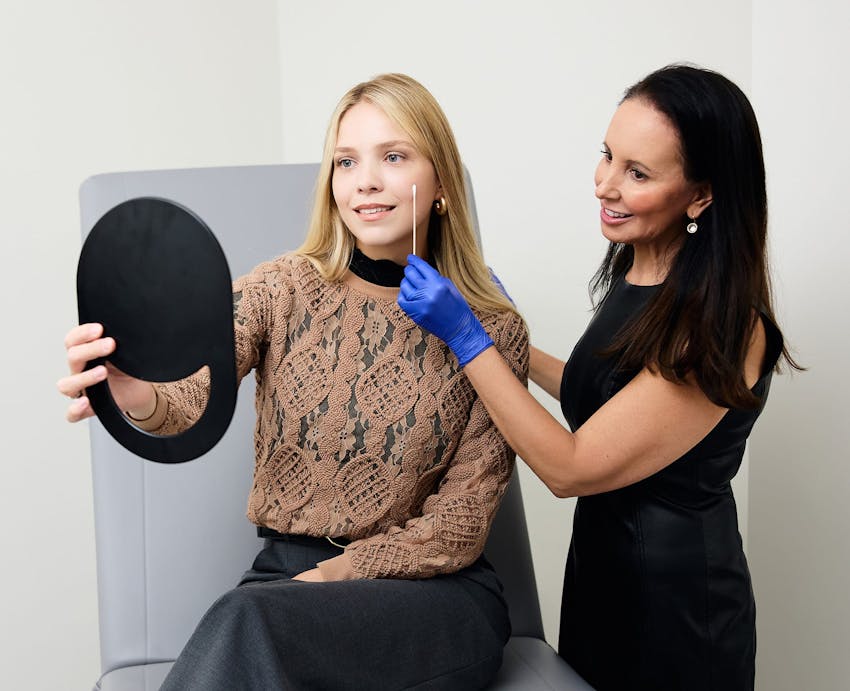 woman looking in a handheld mirror