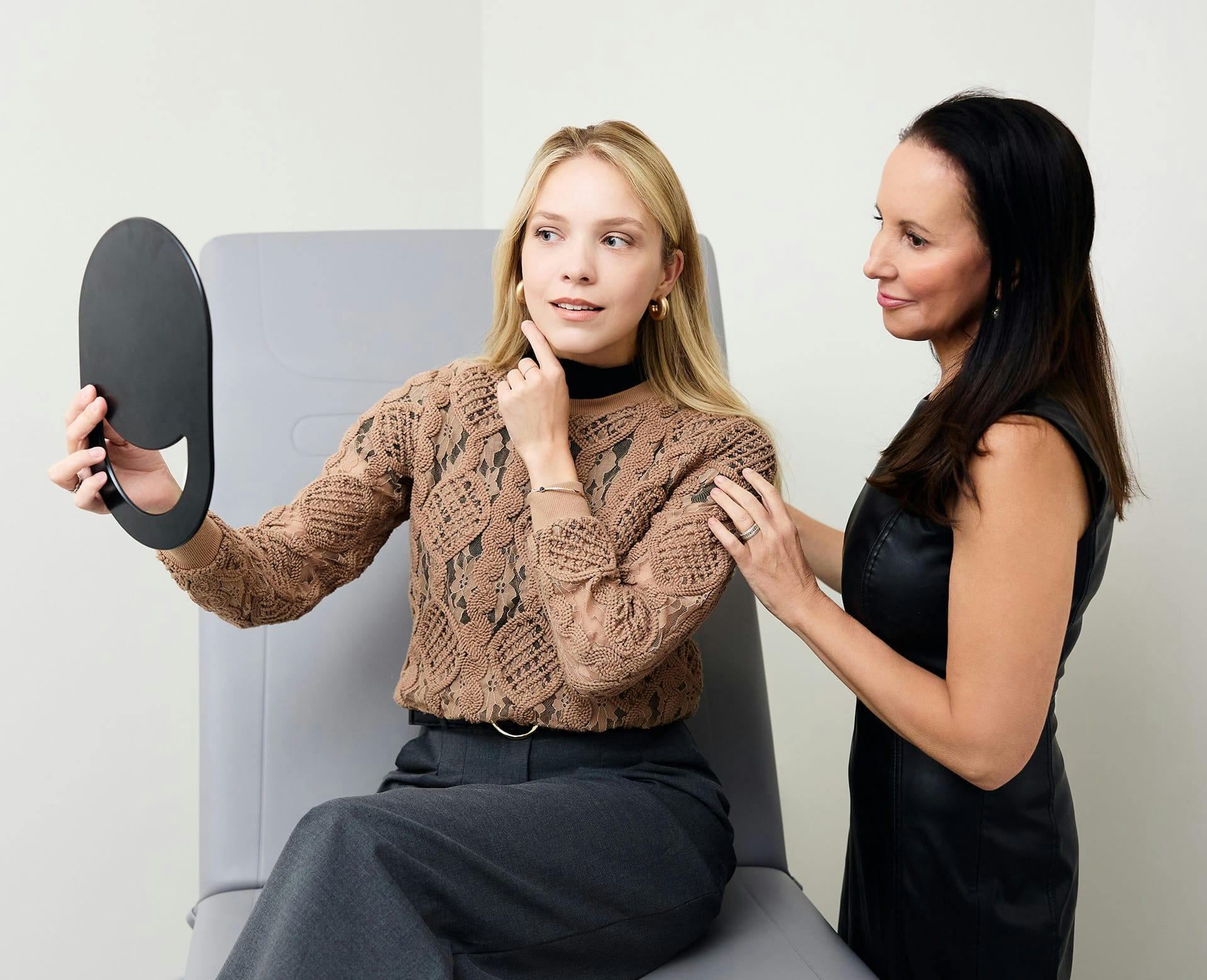 patient looking at her results in a handheld mirror