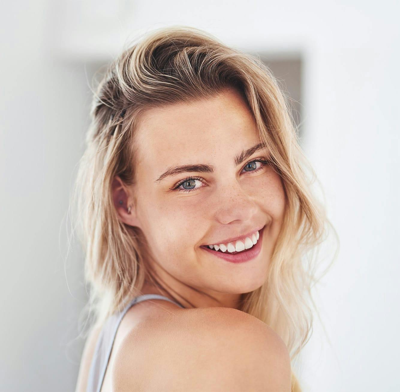 woman with blonde hair smiling over her shoulder