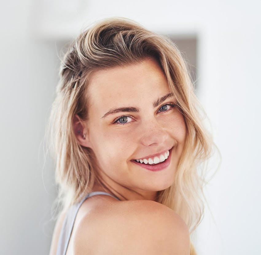 woman with blonde hair smiling over her shoulder