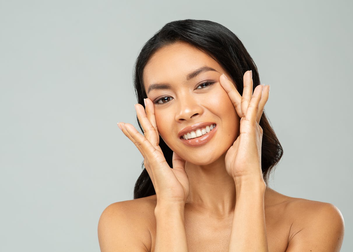 smiling woman with brown hair cupping her face with her hands