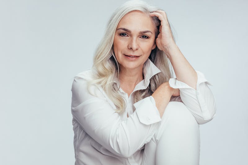 Beautiful older woman with long gray hair smiles at camera in a studio shoot