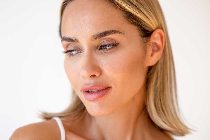 Woman in studio shoot with hair tucked back to show off her ears. This is to emulate the potential results of an ear surgery in Boston with Dr. Ahn