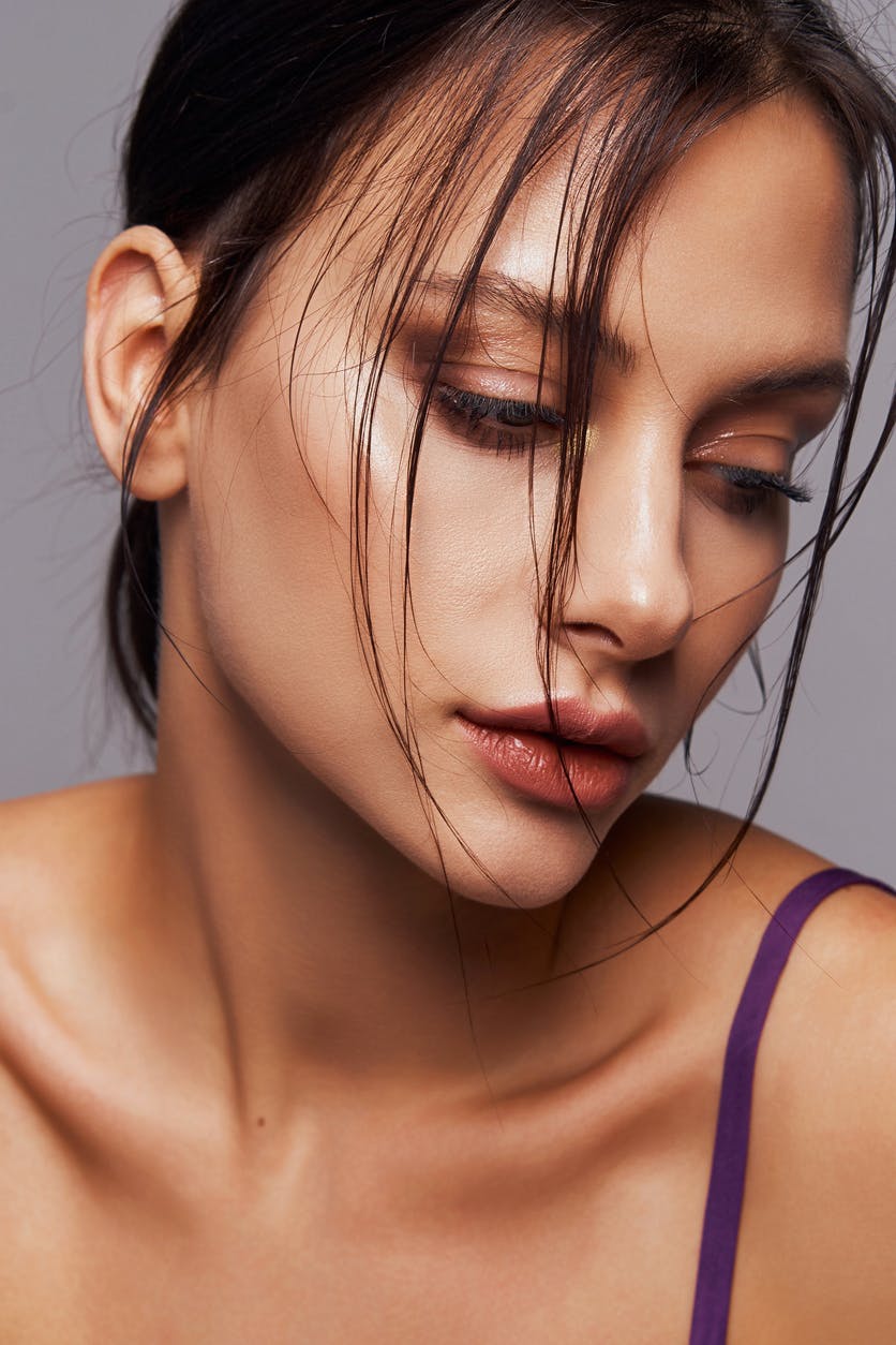Woman in studio shoot with hair tied back shows off her ears. This is to emulate the potential results of an ear surgery in Boston with Dr. Ahn