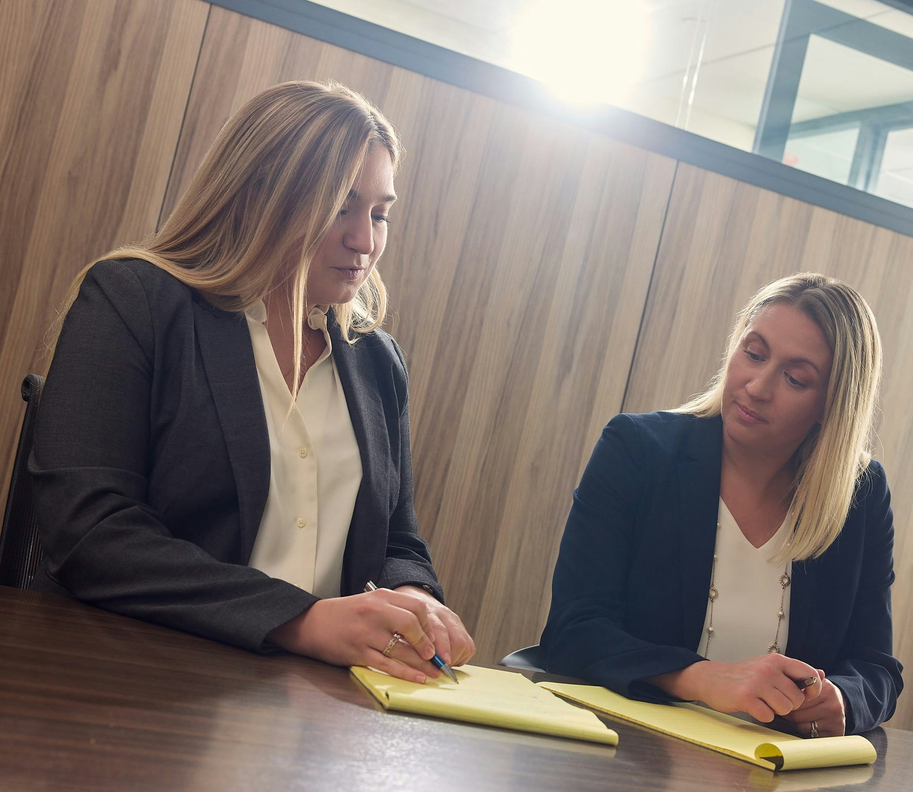 both female attorneys sitting together taking notes