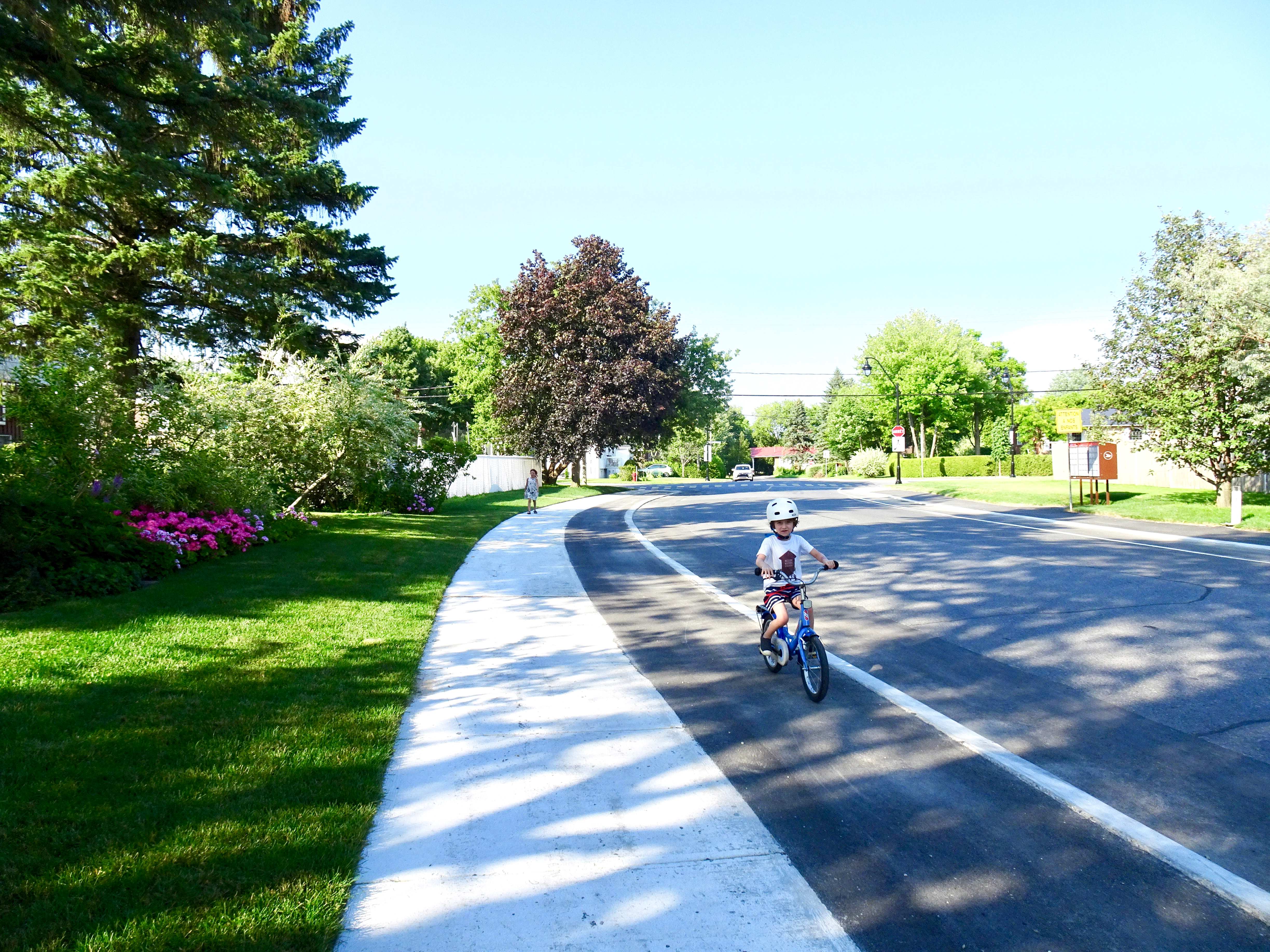 Enfant cycliste circulant sur une infrastructure cyclable sécurisée, surélevée au niveau du trottoir