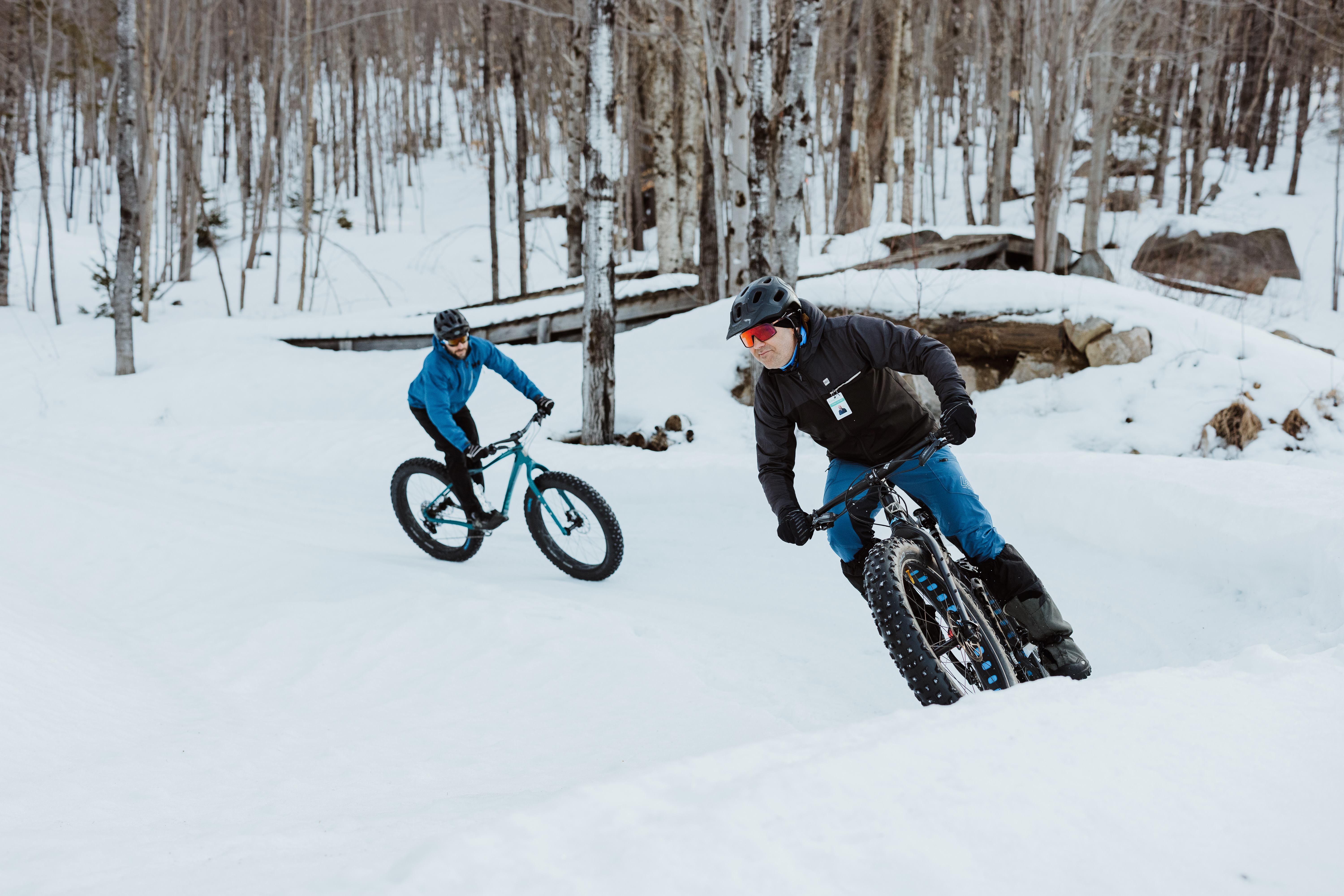 Two cyclists on fatbikes on a snowy trail in the woods