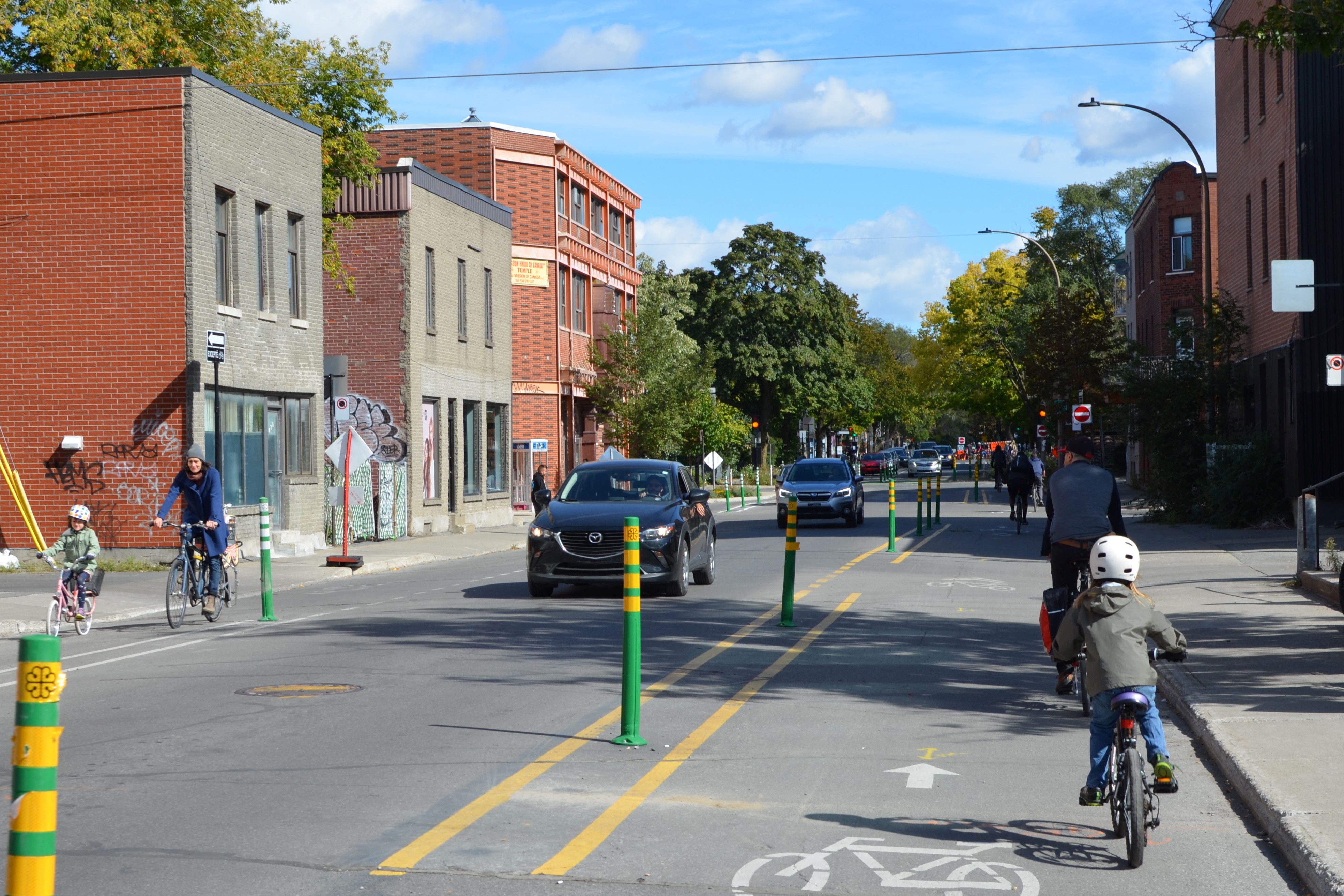 Street shared more equitably between pedestrians (pavements), cyclists (two one-way lanes with families cycling on them) and motorists