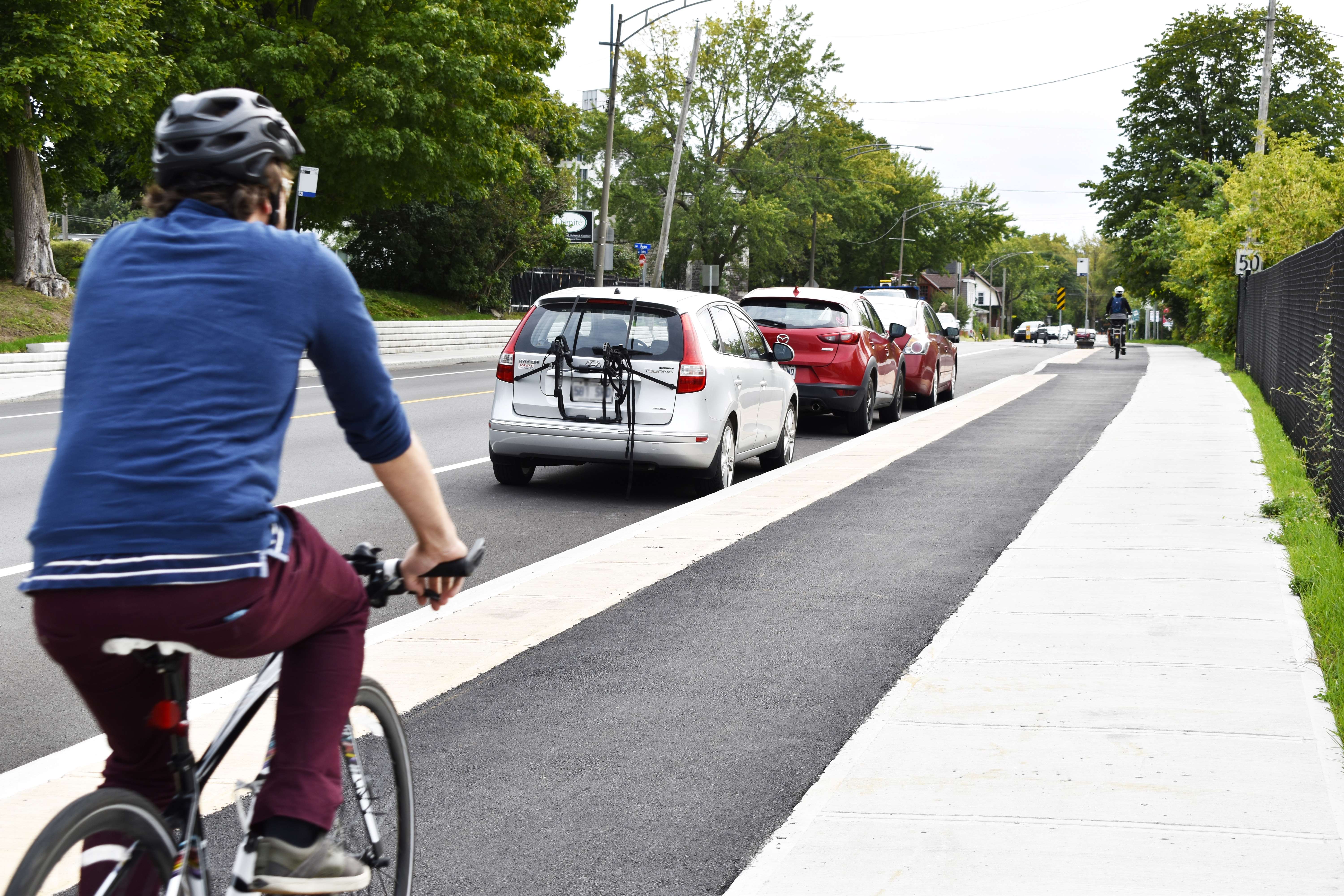 Cycliste circulant sur une piste cyclable surélevée au niveau du trottoir