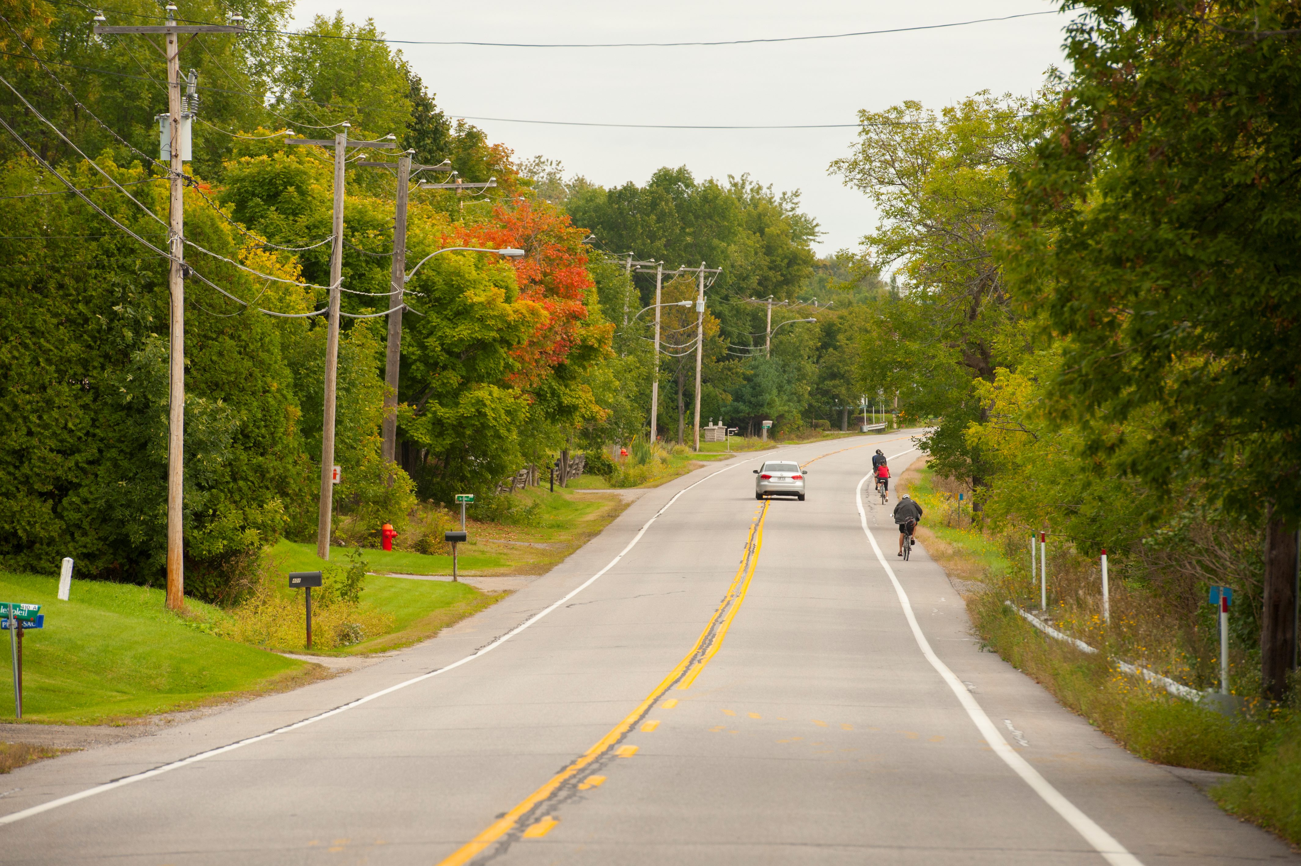 Group of cyclists riding on a paved shoulder in a rural area