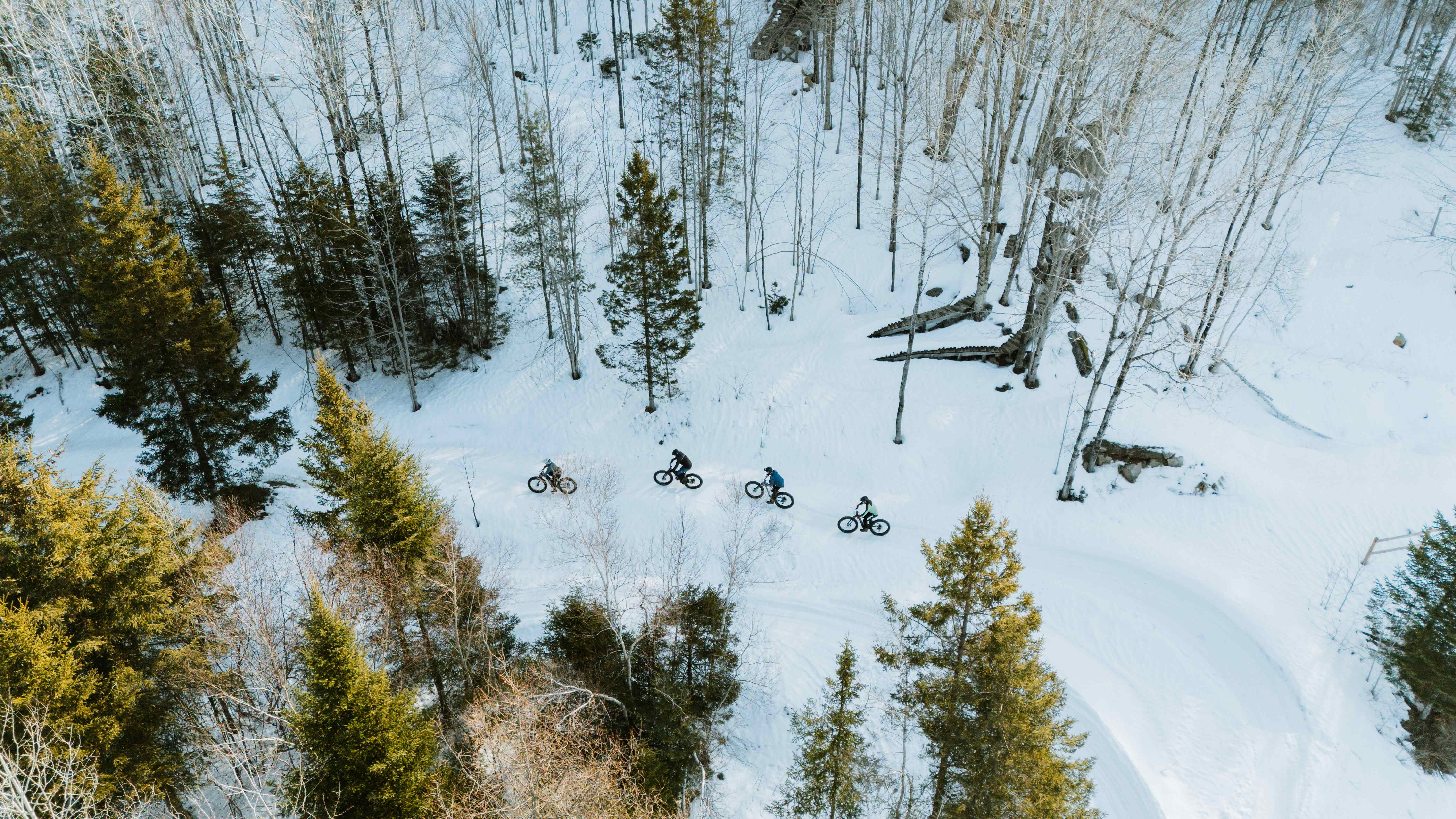 Group of cyclists riding fatbikes on a snowy trail seen from above