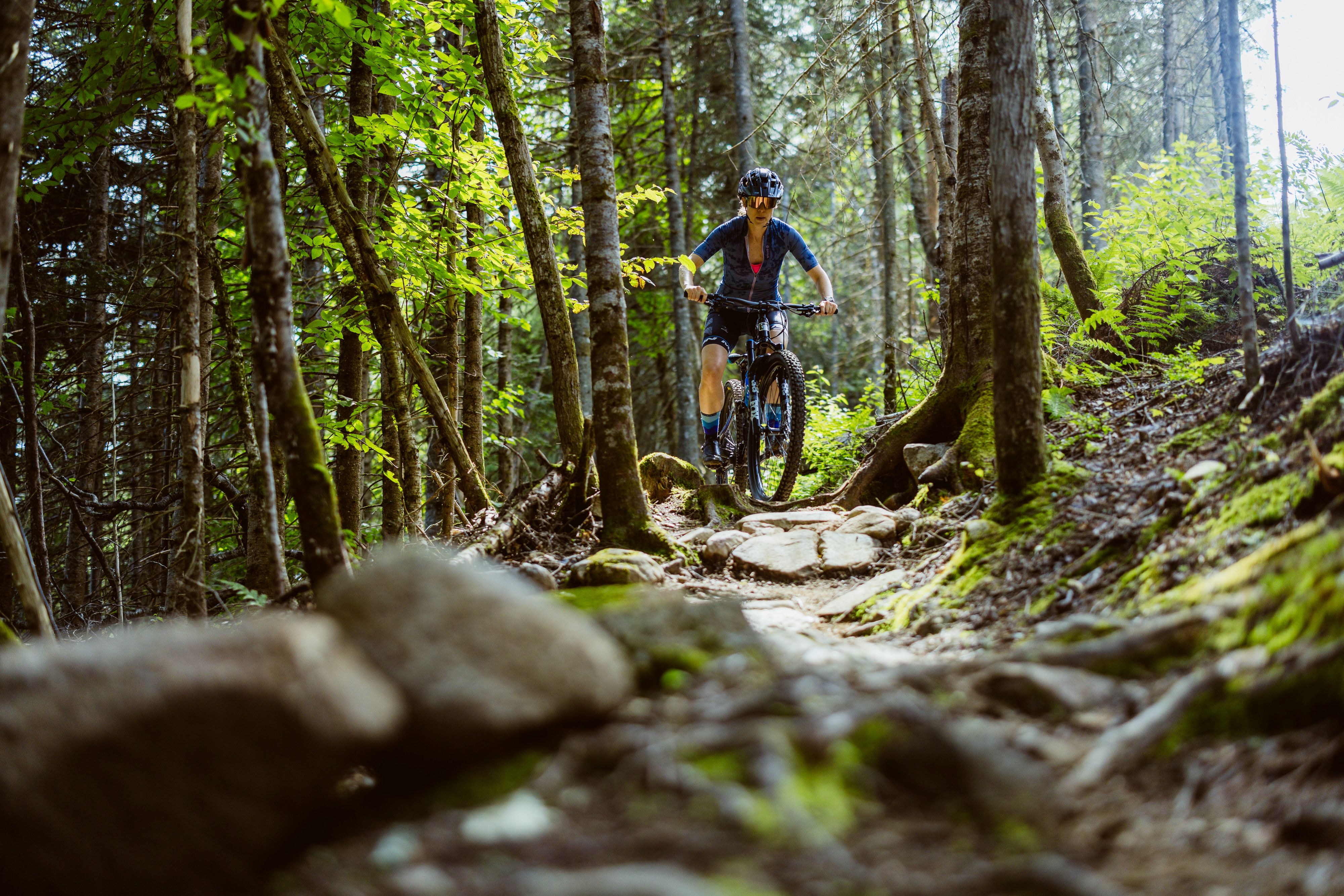 Pratiquante de vélo de montagne (cross-country) sur un sentier dans les bois