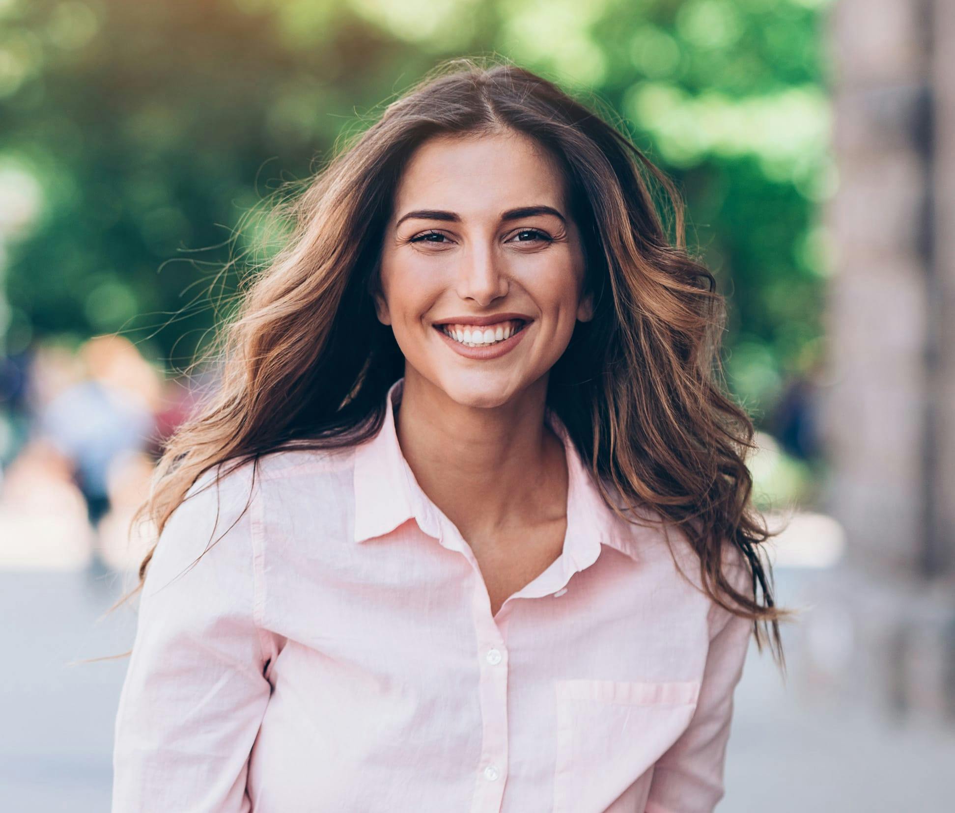 woman in pink shirt smiling with her hair flowing