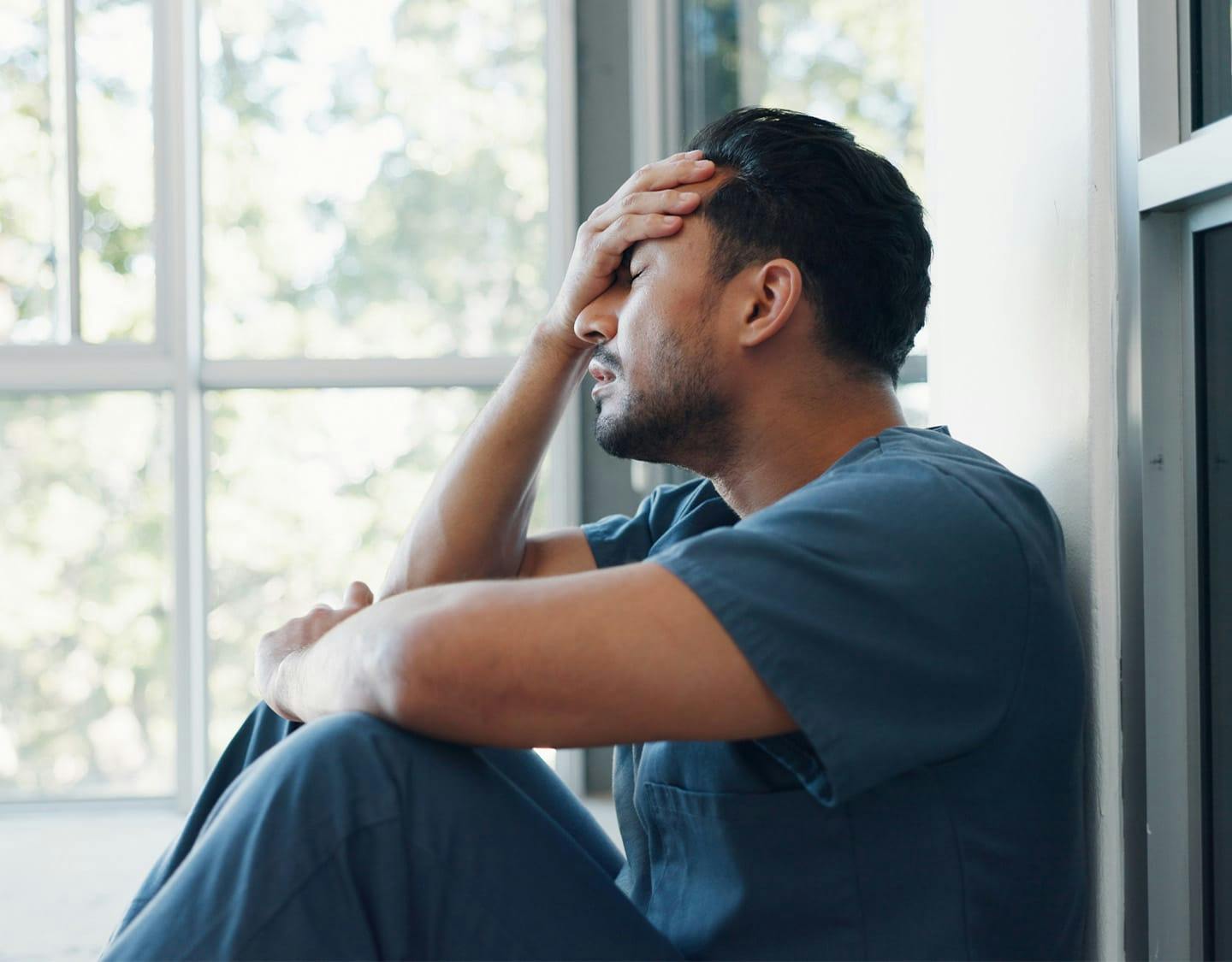 man sititng on the ground, holding his head