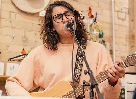 Musician performing with a guitar and signing at Tiny Record Shop.