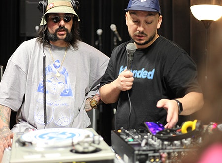 Two DJ's performing in front of DJ setup.