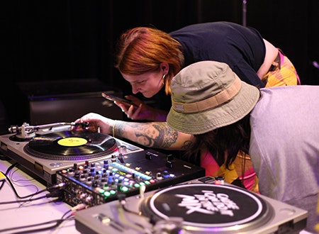 Two people closely examining DJ equipment.