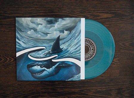 Aqua blue vinyl record in a sleeve featuring a shark illustration, part of the Protest the Hero 'Pacific Myth' vinyl box set.