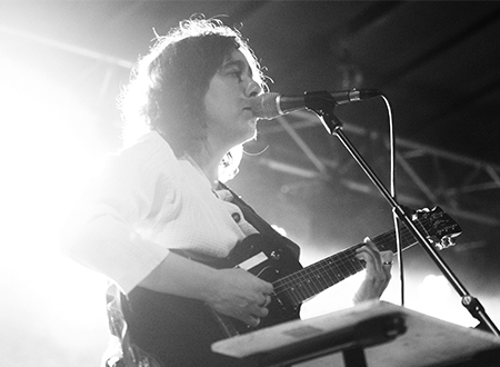 Musician singing and playing guitar onstage.