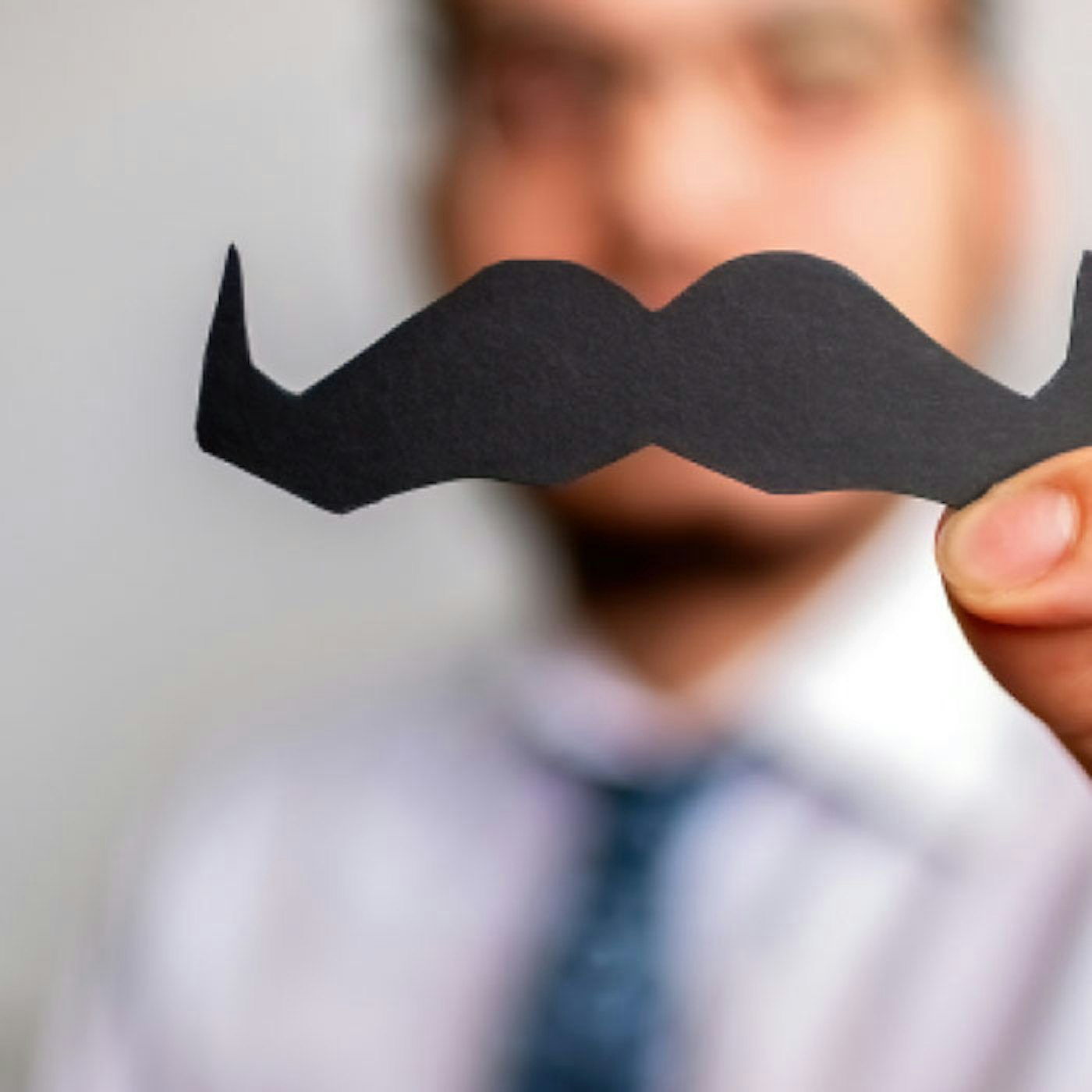 Man holding a cutout of a moustache