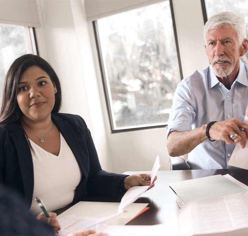 two people sitting at a table with documents