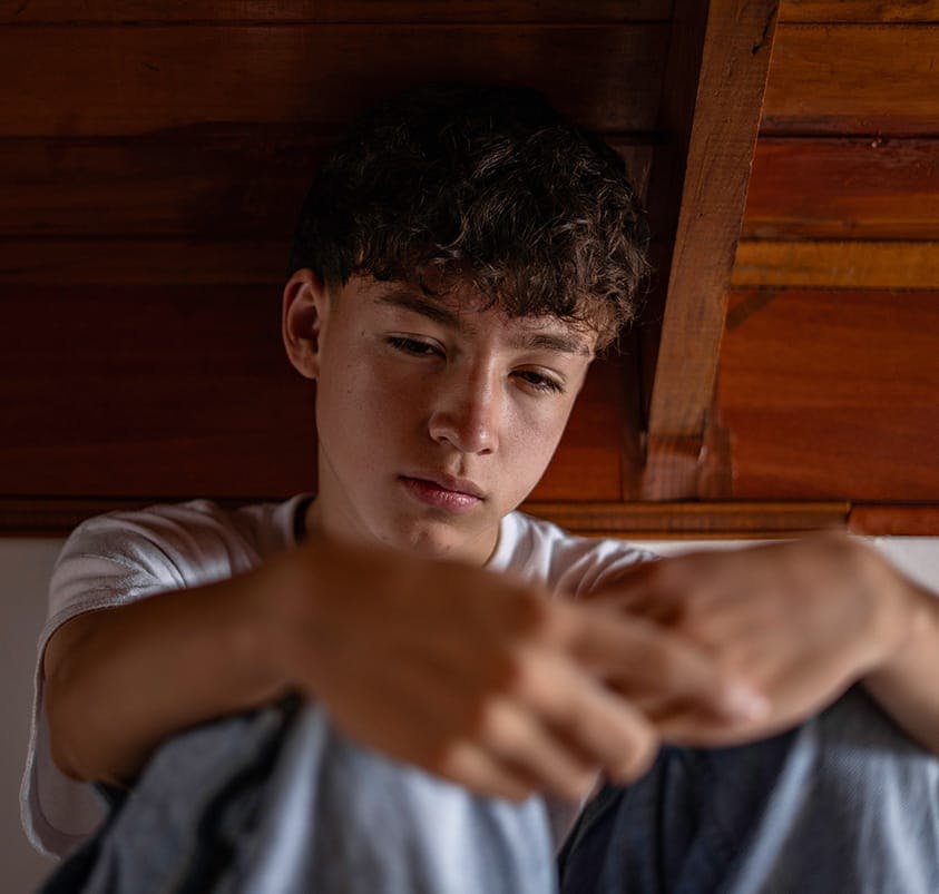 young man sitting on ground, looking sad