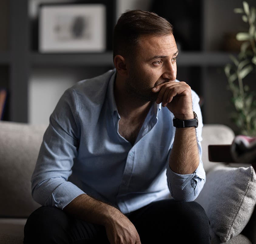 man sitting on a couch resting his chin on his hand