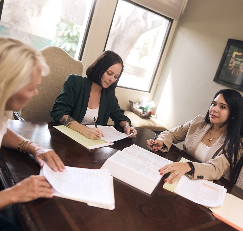 three women sitting at a table looking at documents