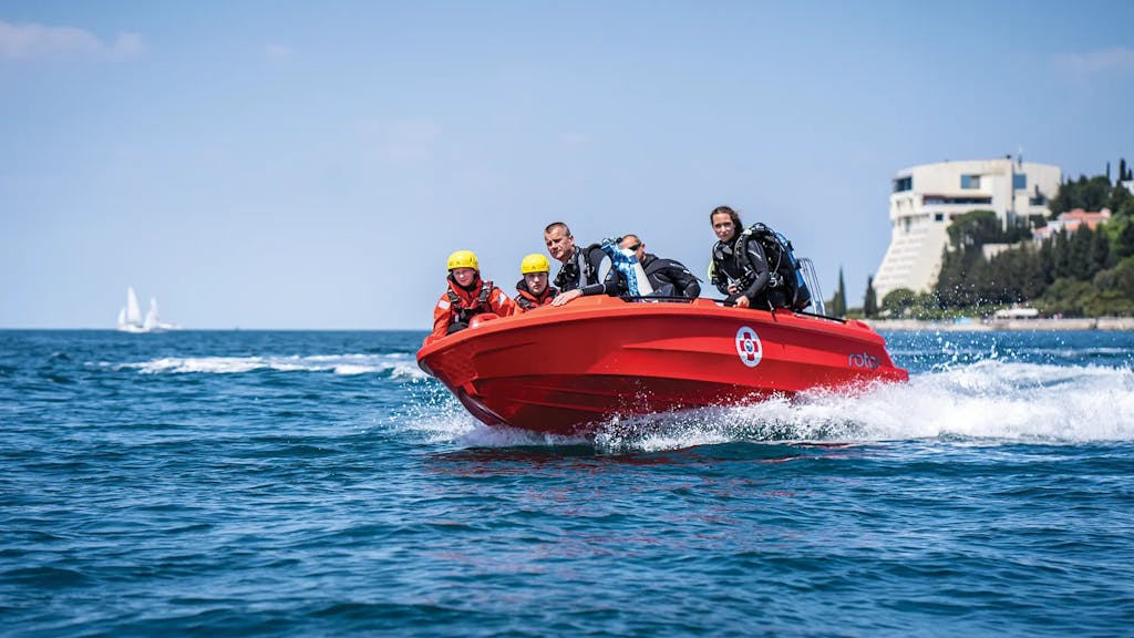 Roto Nautica Hydra 450 rescue boat cutting through waves with a team of rescuers on a high-speed sea rescue mission.
