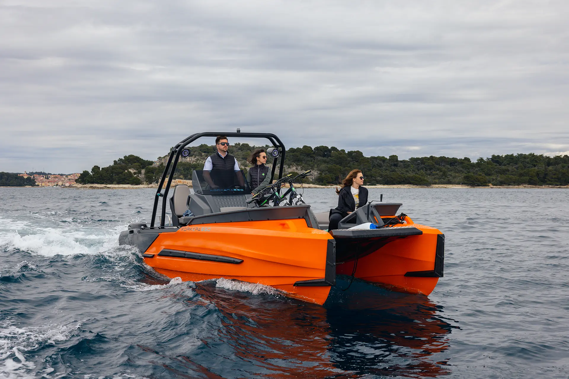 Captain steering the Korkyra 650 Pro catamaran boat while passengers enjoy the ride.