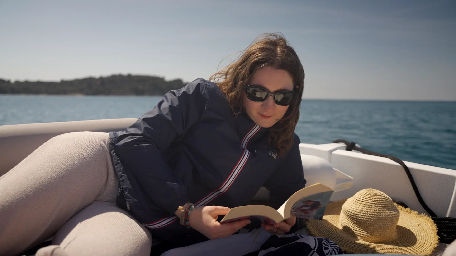 Woman reading a book on the deck of a Hydra boat.