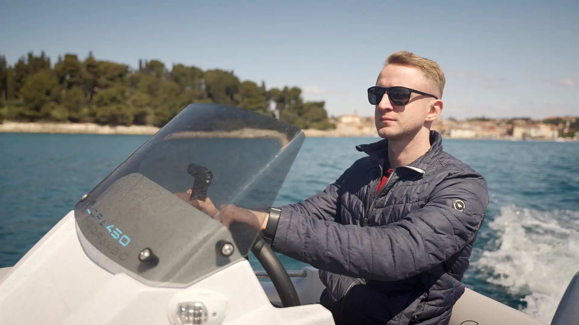 Man steering a Roto Nautica boat on calm waters.