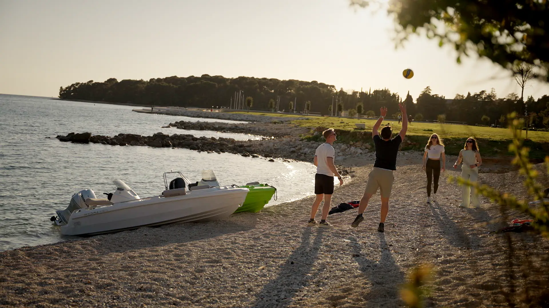 Friends playing beach volleyball with a Roto Nautica boat in the background.