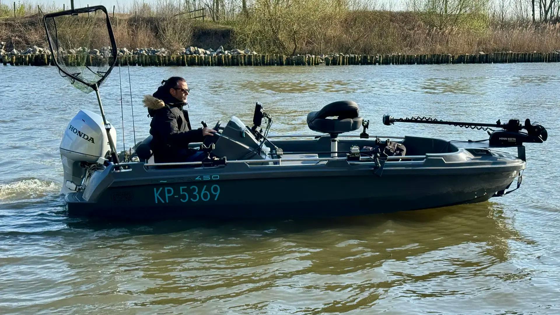 A man driving a Hydra 450 fishing boat across the water, heading out to fish