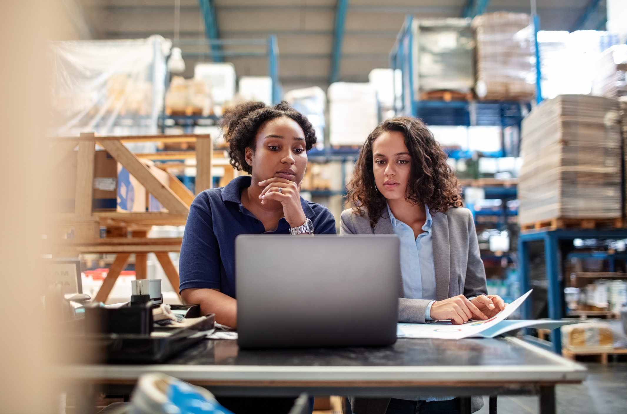 Two women at a computer in a manufacturing floor