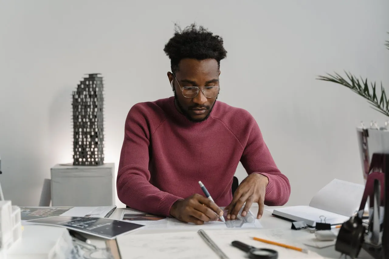 Focused architect or designer working on blueprints at a desk, surrounded by design tools, showcasing creativity and precision.