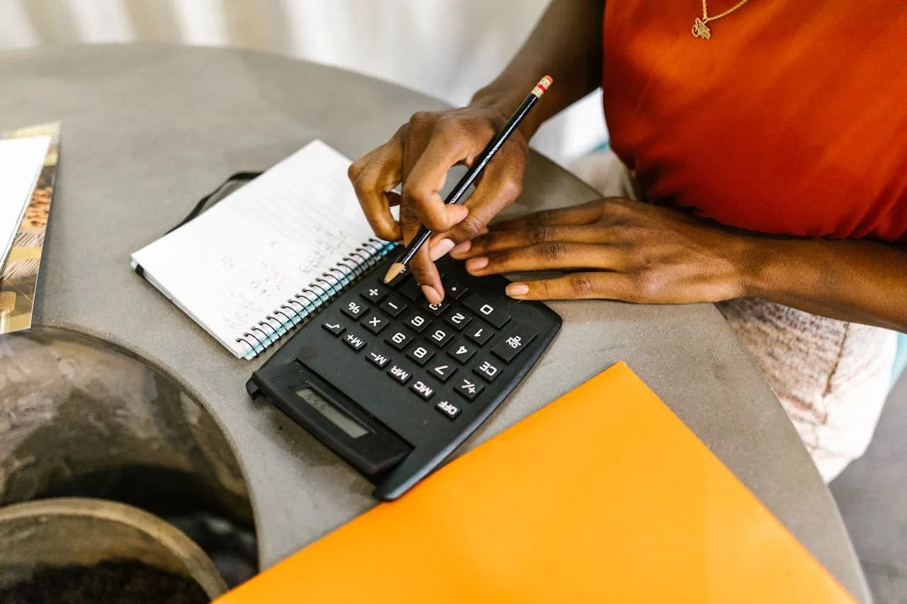 Close-up of a person using a calculator with a pencil and notebook, symbolizing budgeting, financial calculations, or business planning.