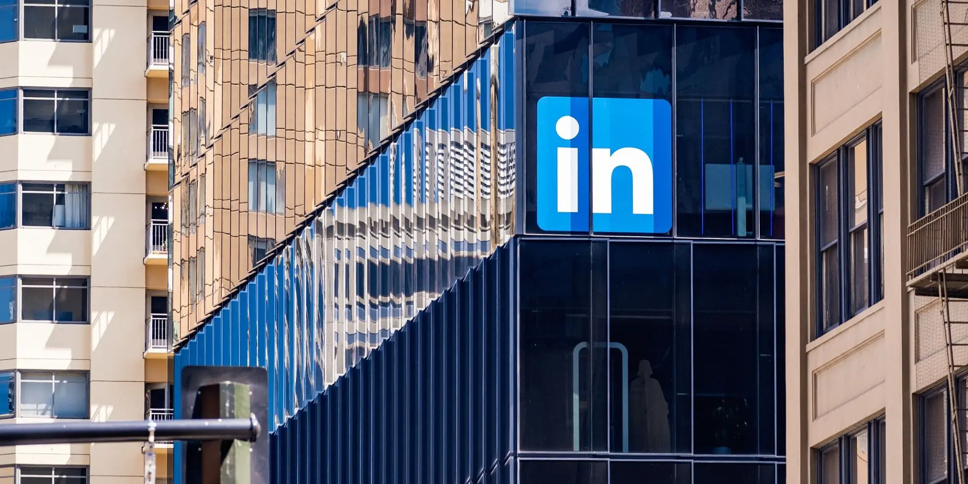 A modern LinkedIn office building with a glass facade reflecting surrounding high-rise buildings. The LinkedIn logo is prominently displayed on the exterior.