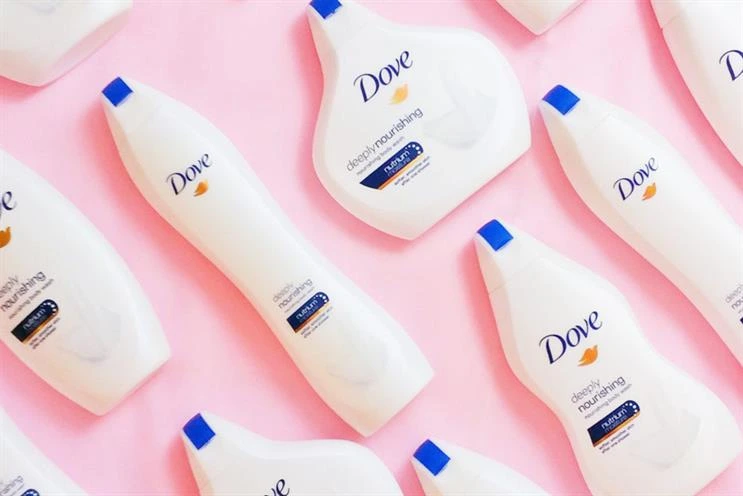 Multiple Dove deeply nourishing body wash bottles arranged on a pastel pink background.