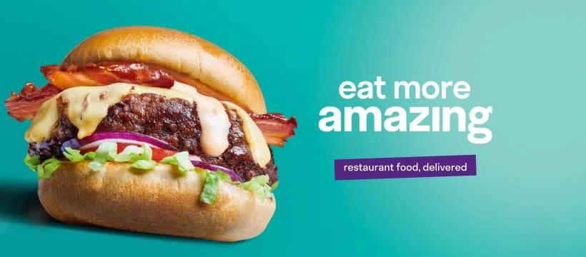 “Close-up of a juicy cheeseburger with lettuce, onion, and bacon on a bun, next to the tagline ‘Eat more amazing’ on a teal background with a note that it’s restaurant food delivered.”