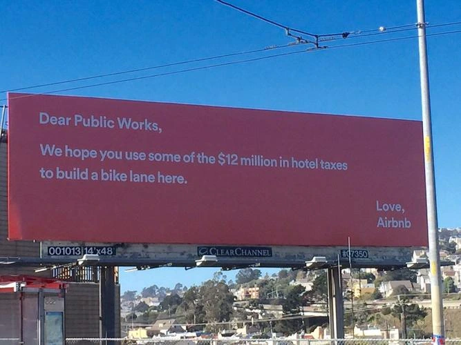 “A red billboard from Airbnb addressed to Public Works, requesting that $12 million in hotel taxes be used to build a bike lane.”