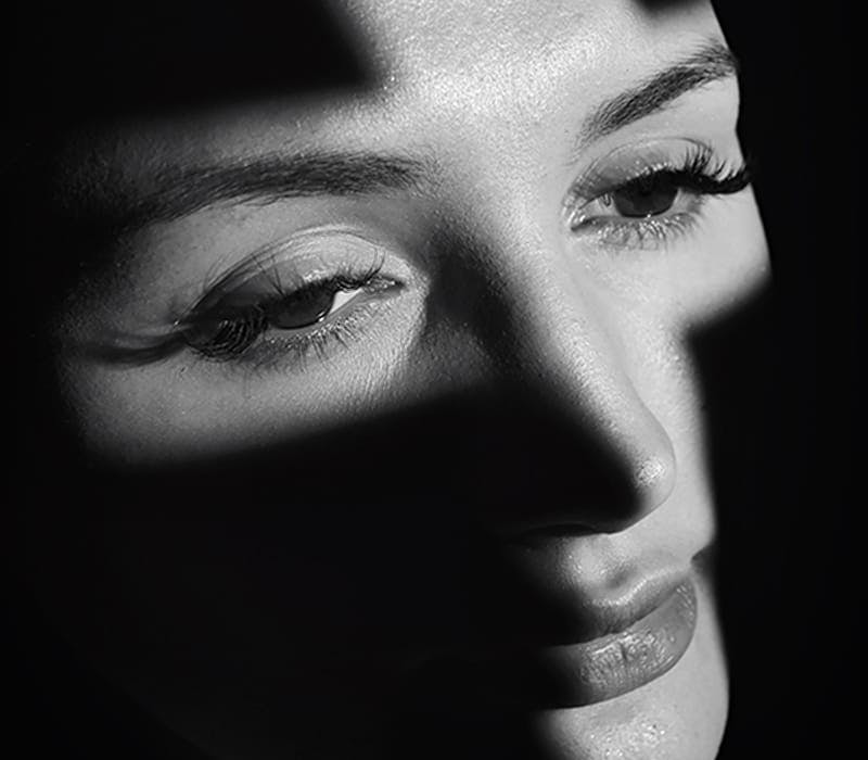 black and white image of a woman's face with shadows on everything but her eyes