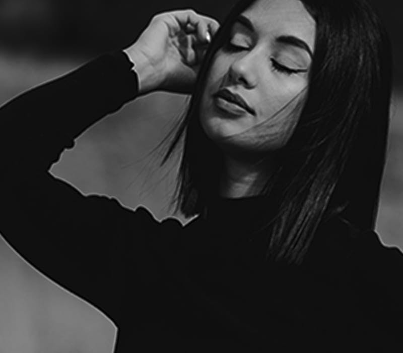 black and white image of a woman touching the side of her face