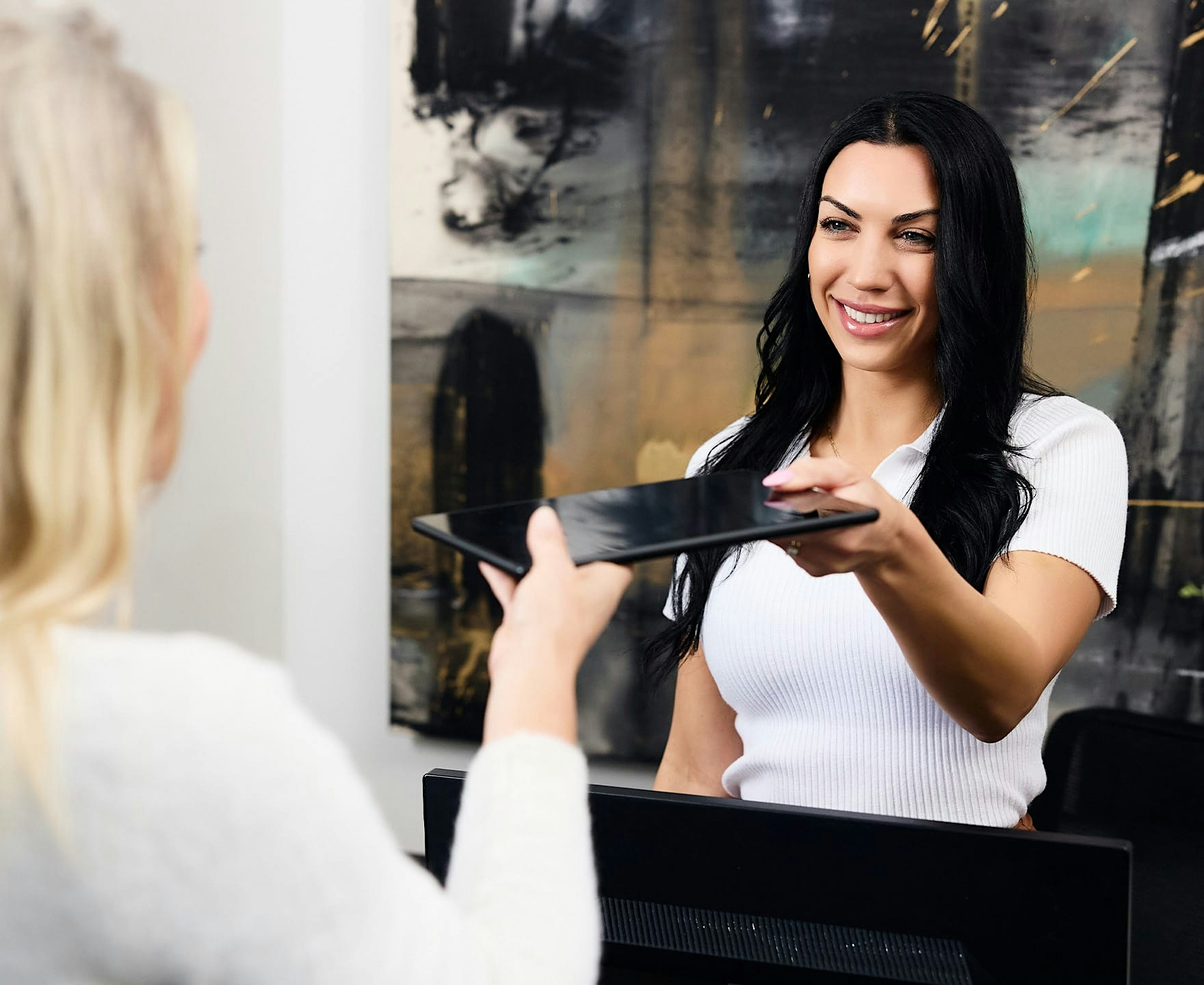woman handing tablet to front desk